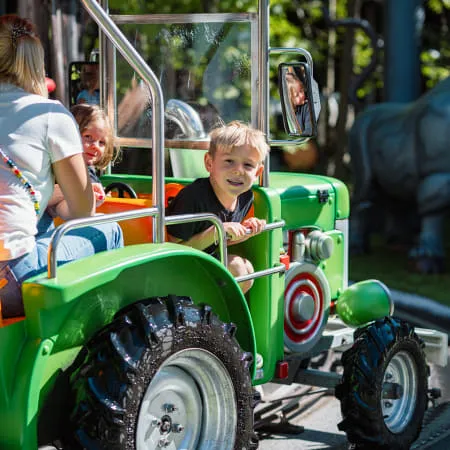 Kinder fahren in einem grünen Spielzeug-Traktor