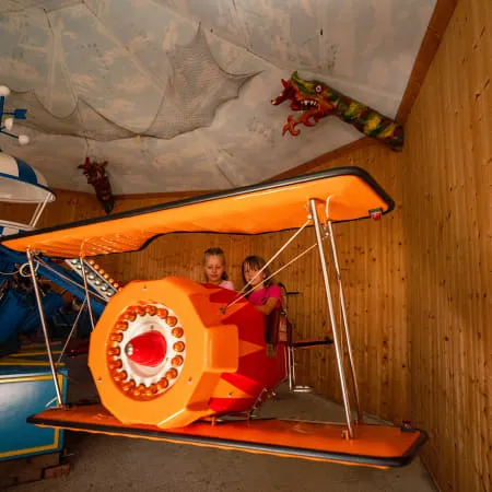 Zwei Kinder in einem orangen Flugzeugspielzeug