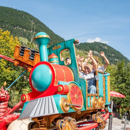 Bunte Kinderachterbahn im Erlebnispark mit jubelnden Fahrgästen