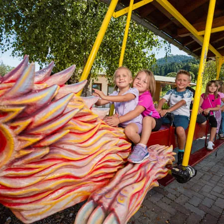 Kinder fahren auf einem Drachenkarussell im Freizeitpark.