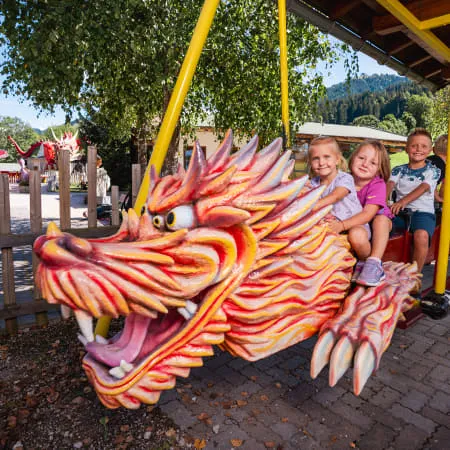 Kinder fahren auf einem Drachenkarussell im Erlebnispark