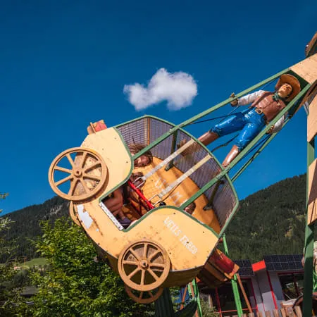 Karussell im Erlebnispark mit blauen Himmel und Bäumen