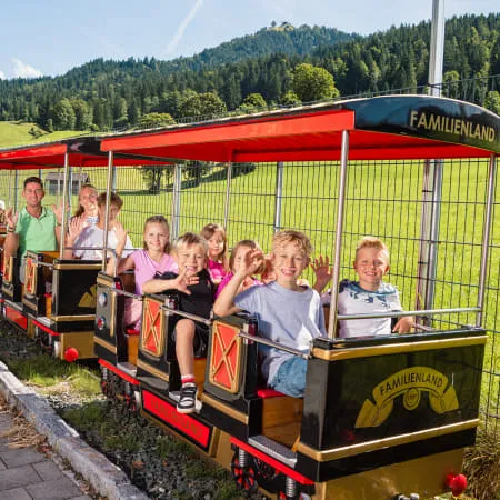 Familien im Zug im Familienland Erlebnispark, Berge im Hintergrund