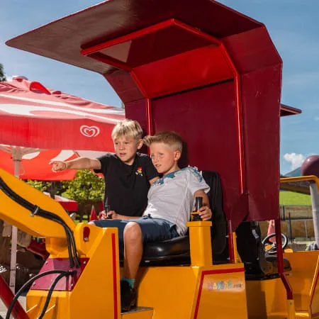 Zwei Kinder sitzen in einem Spielzeug-Baumaschine