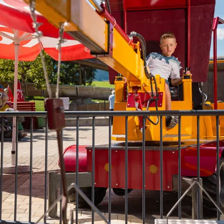 Junge sitzt in einem Spielzeugkran im Erlebnispark