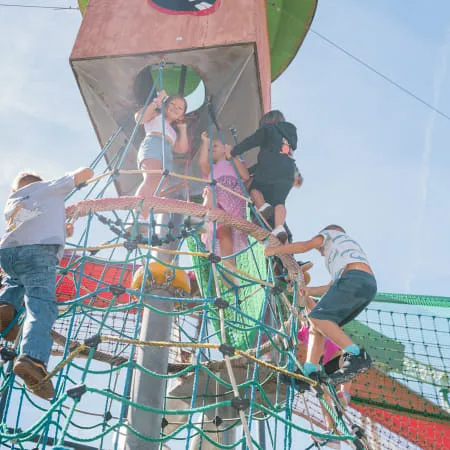 Kinder spielen an einem Kletterturm im Erlebnispark.