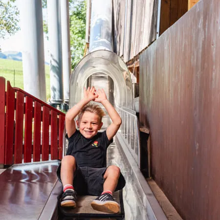 Kind rutscht mit Freude eine Rutsche im Erlebnispark hinunter