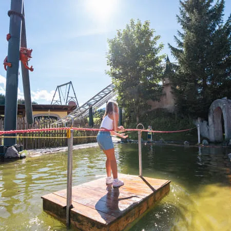 Mädchen steht auf einem Holzplatz neben einem Wasserlauf