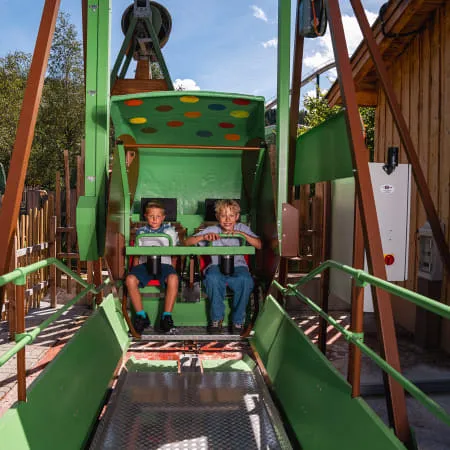 Zwei Kinder sitzen in einem Fahrgeschäft im Erlebnispark