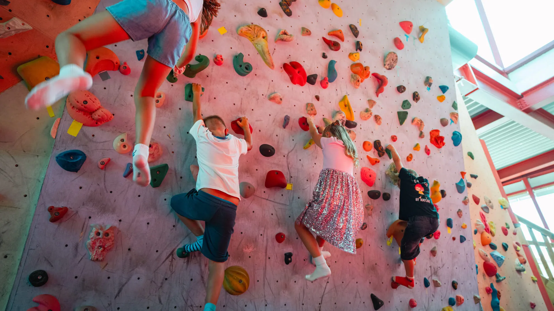 Kinder klettern an einer bunten Kletterwand im Familienland