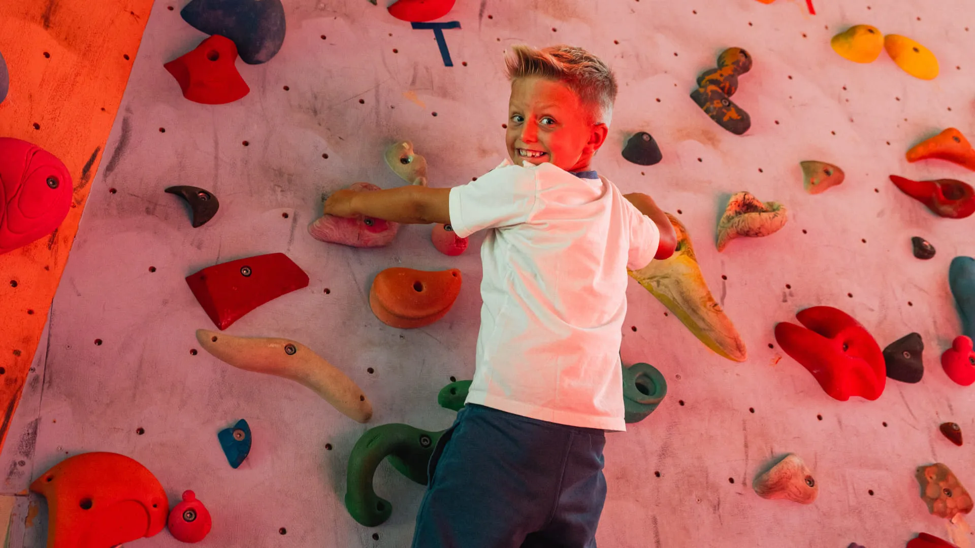 Junge klettert an bunter Kletterwand im Erlebnispark