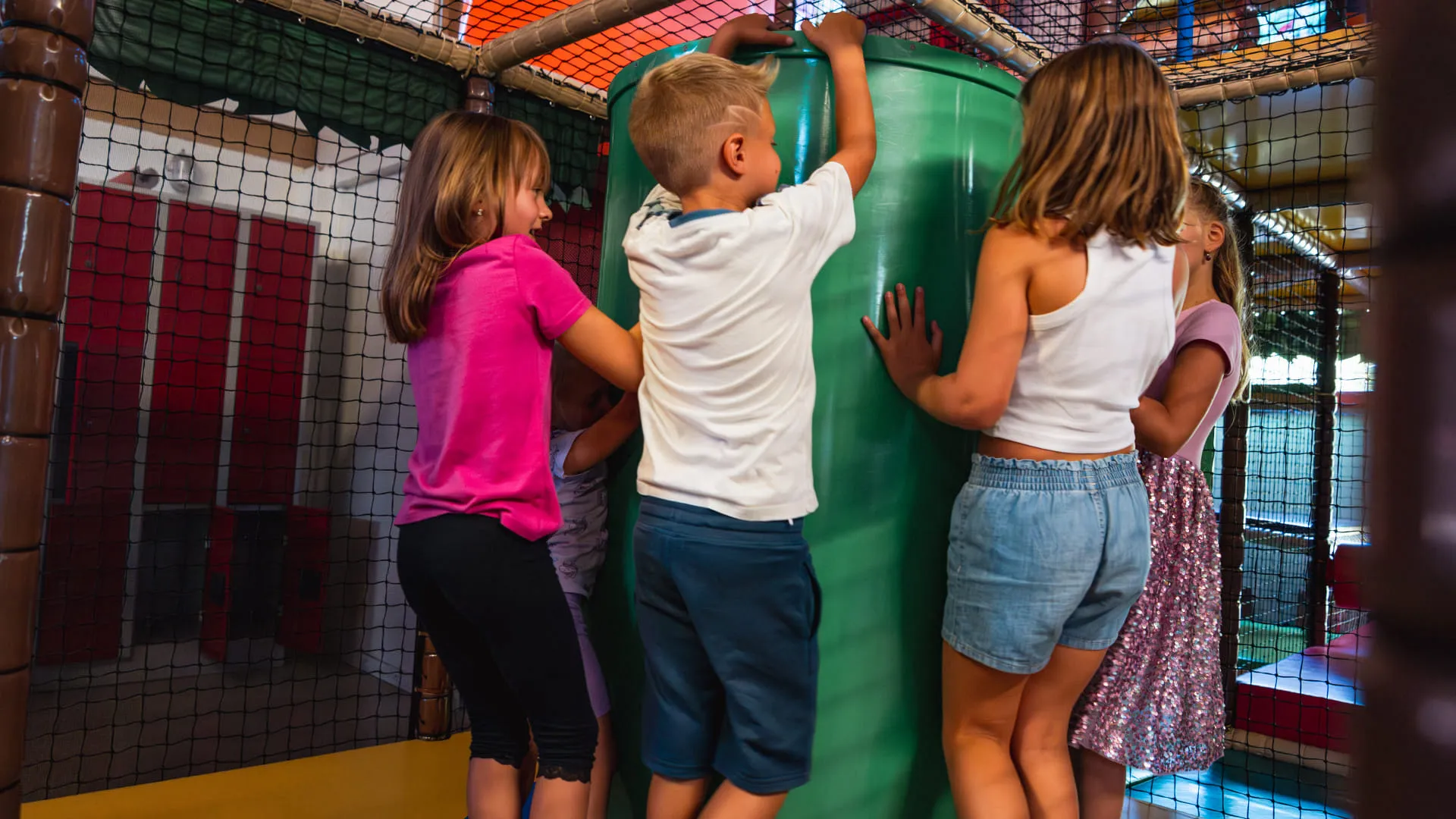 Kinder spielen in einem Indoor-Spielbereich mit Kletterelementen.